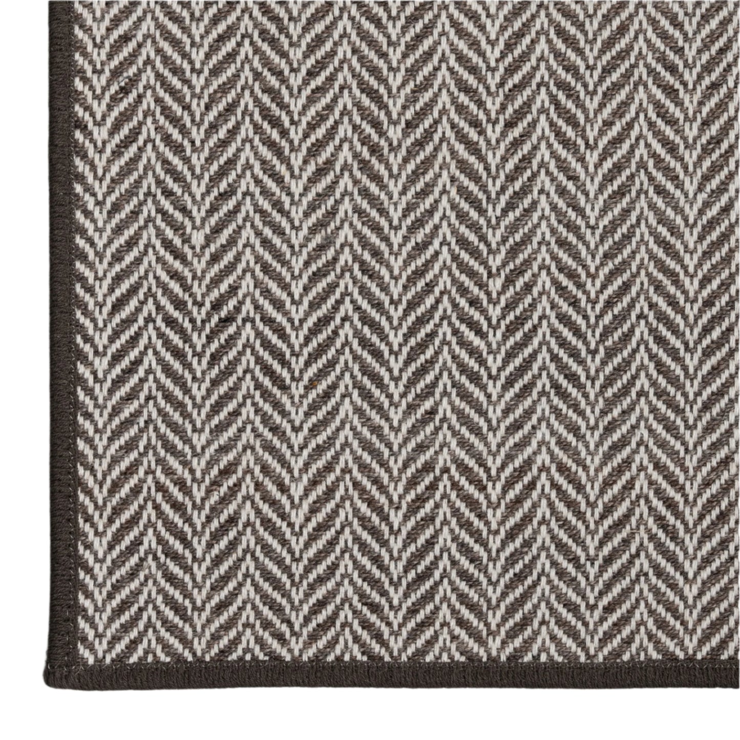 Close-up of a gray and white herringbone patterned rug on a light gray background