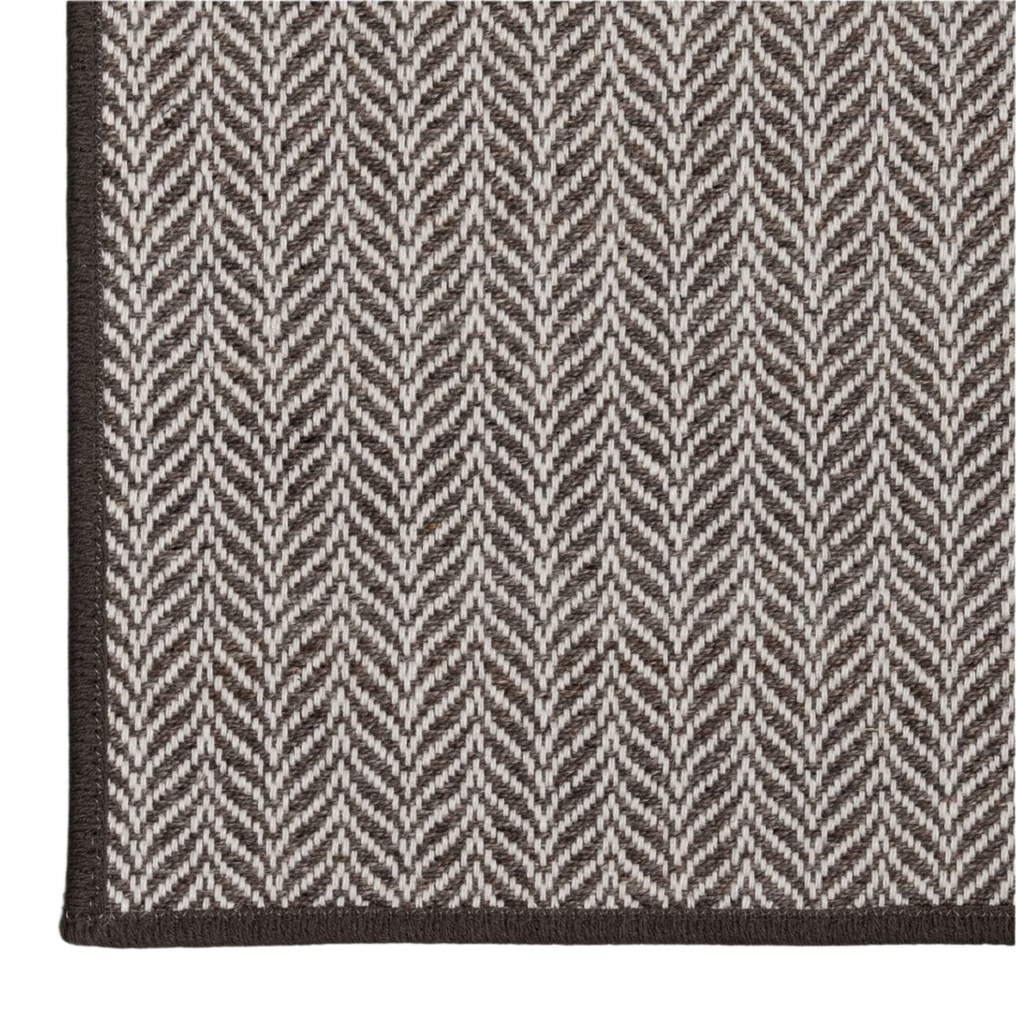 Close-up of a gray and white herringbone patterned rug on a light gray background