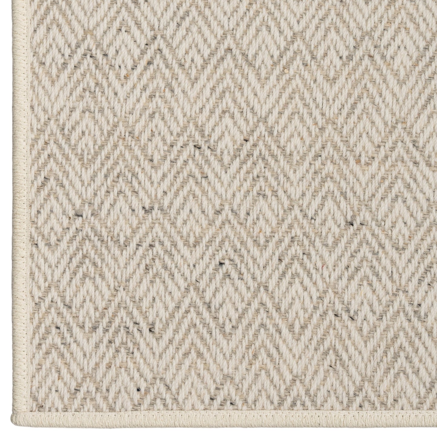 Close-up of a textured beige rug with a diamond pattern