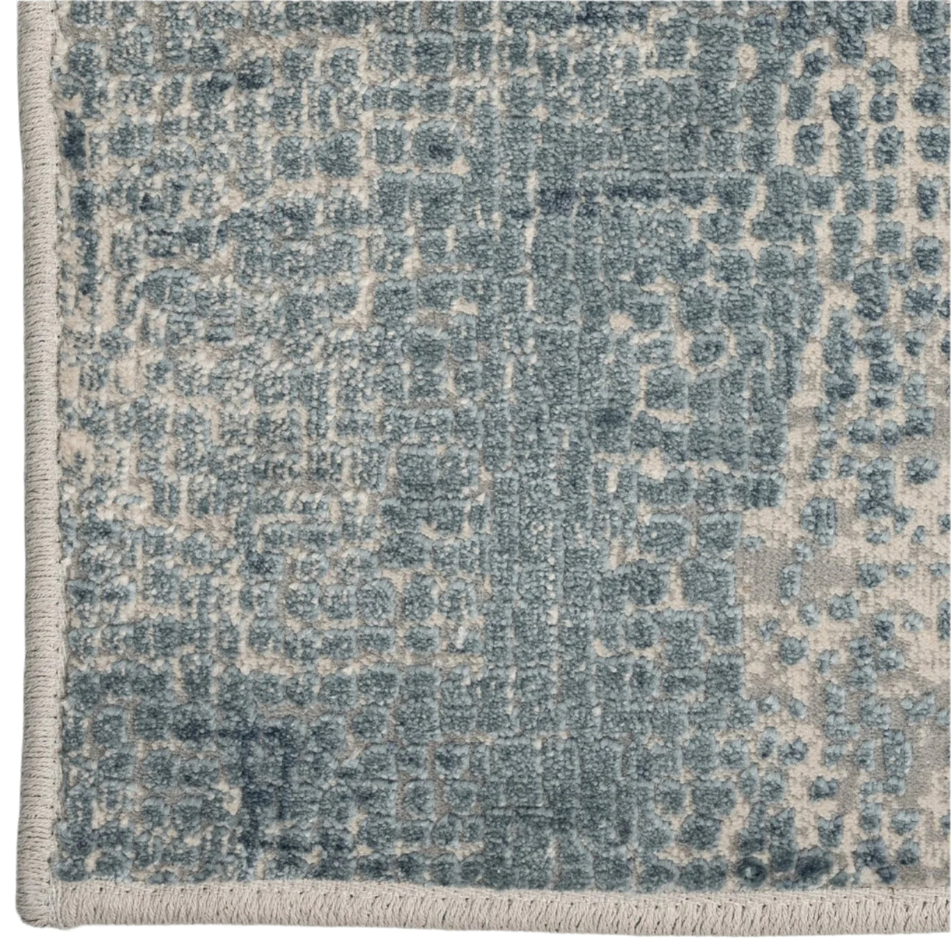 Close-up of a textured blue and beige area rug with a geometric pattern.
