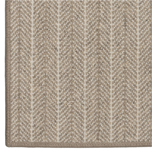 Close-up of a textured beige carpet with a subtle chevron pattern on a white background