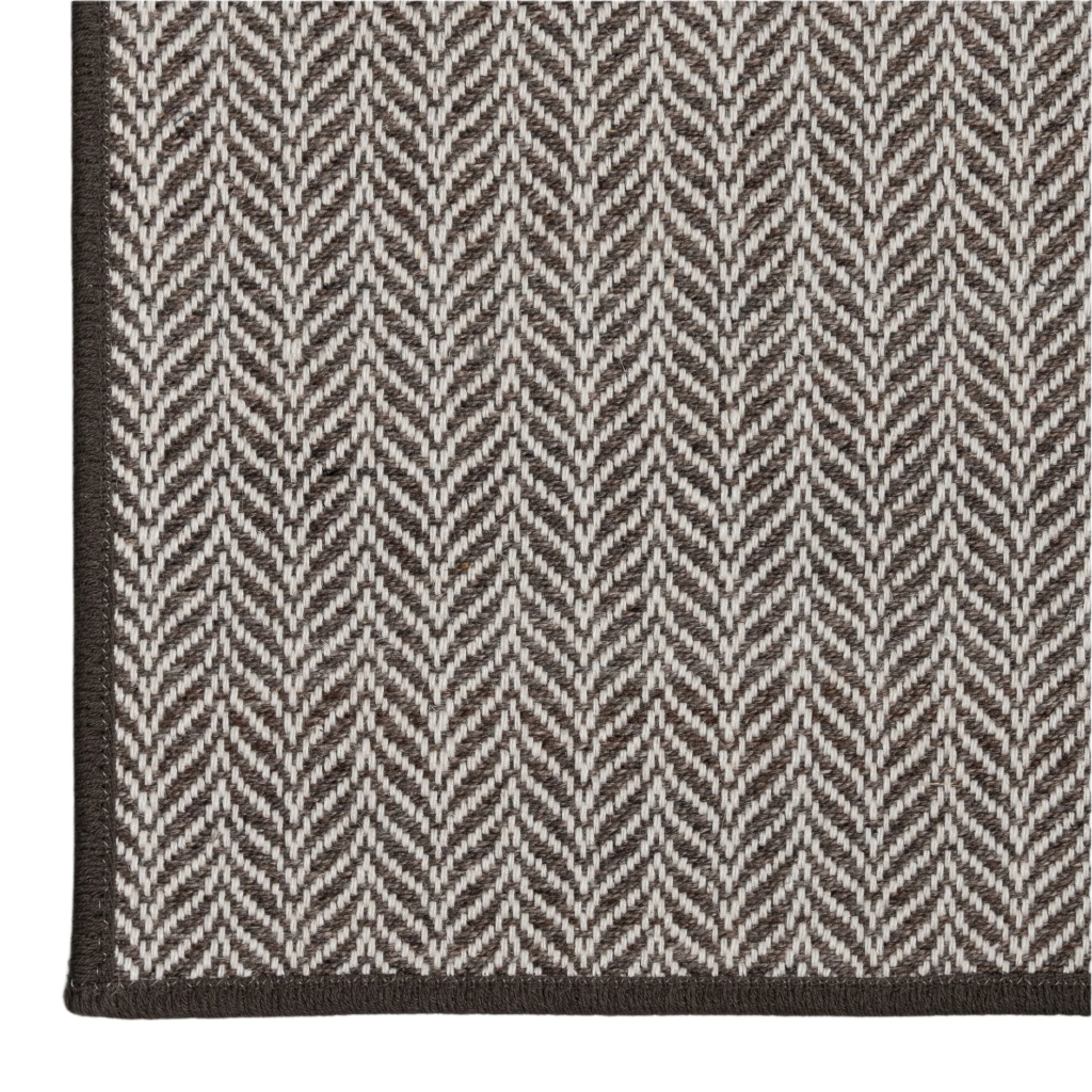 Close-up of a gray and white herringbone patterned rug on a light gray background
