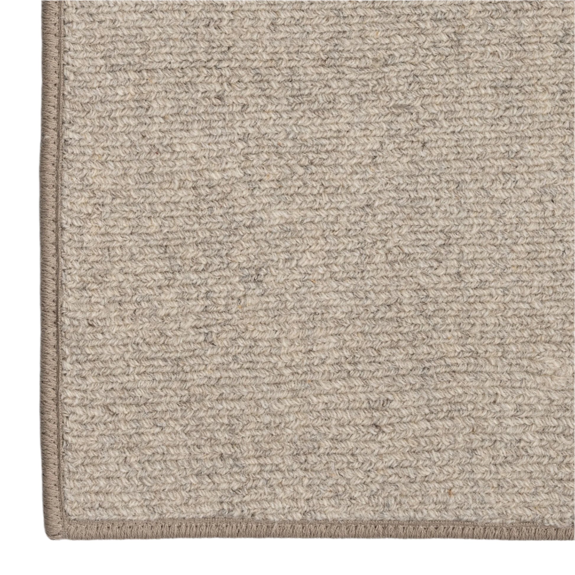 Close-up of a textured beige rug corner on a white background