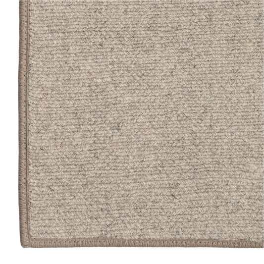 Close-up of a textured beige rug corner on a white background