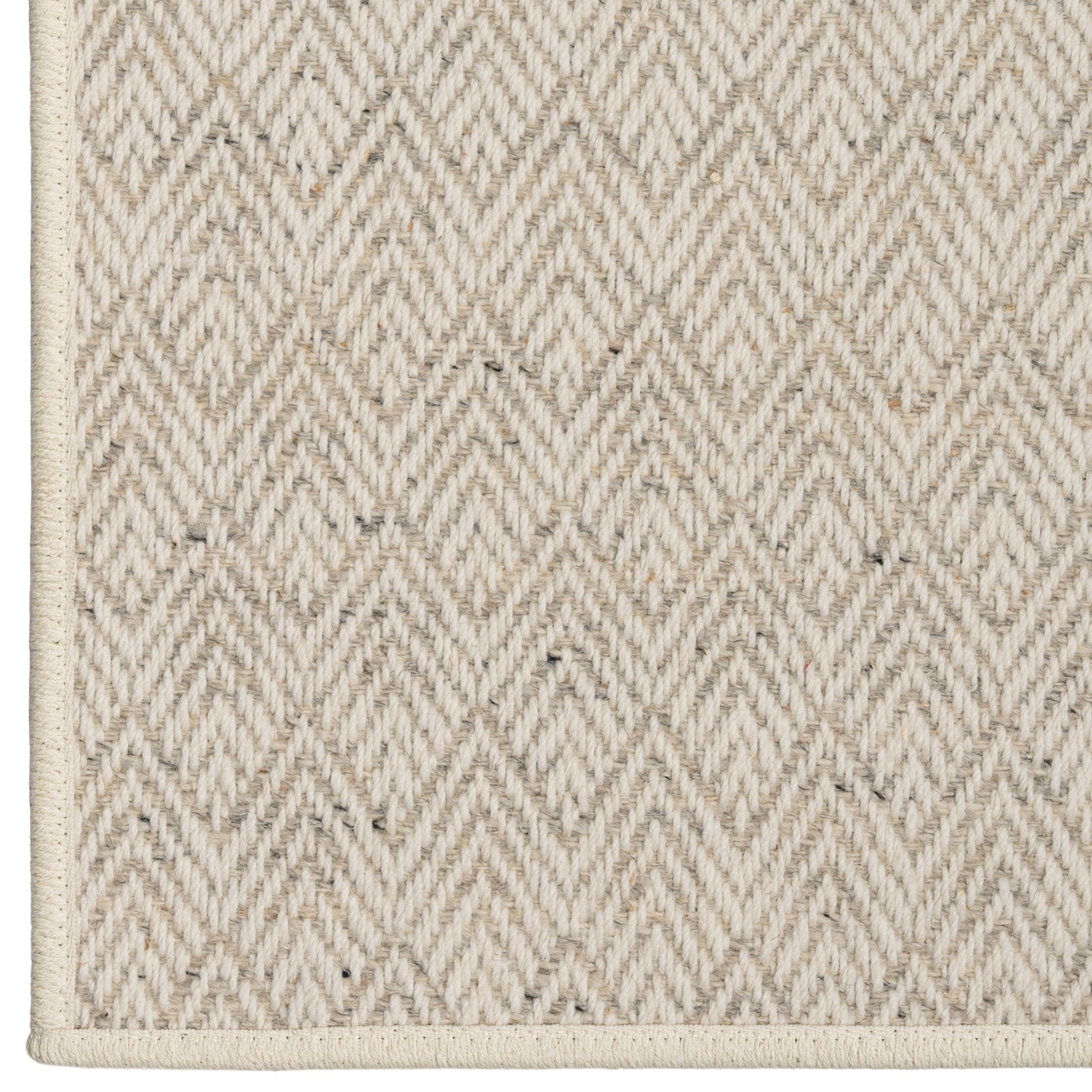 Close-up of a textured beige rug with a diamond pattern