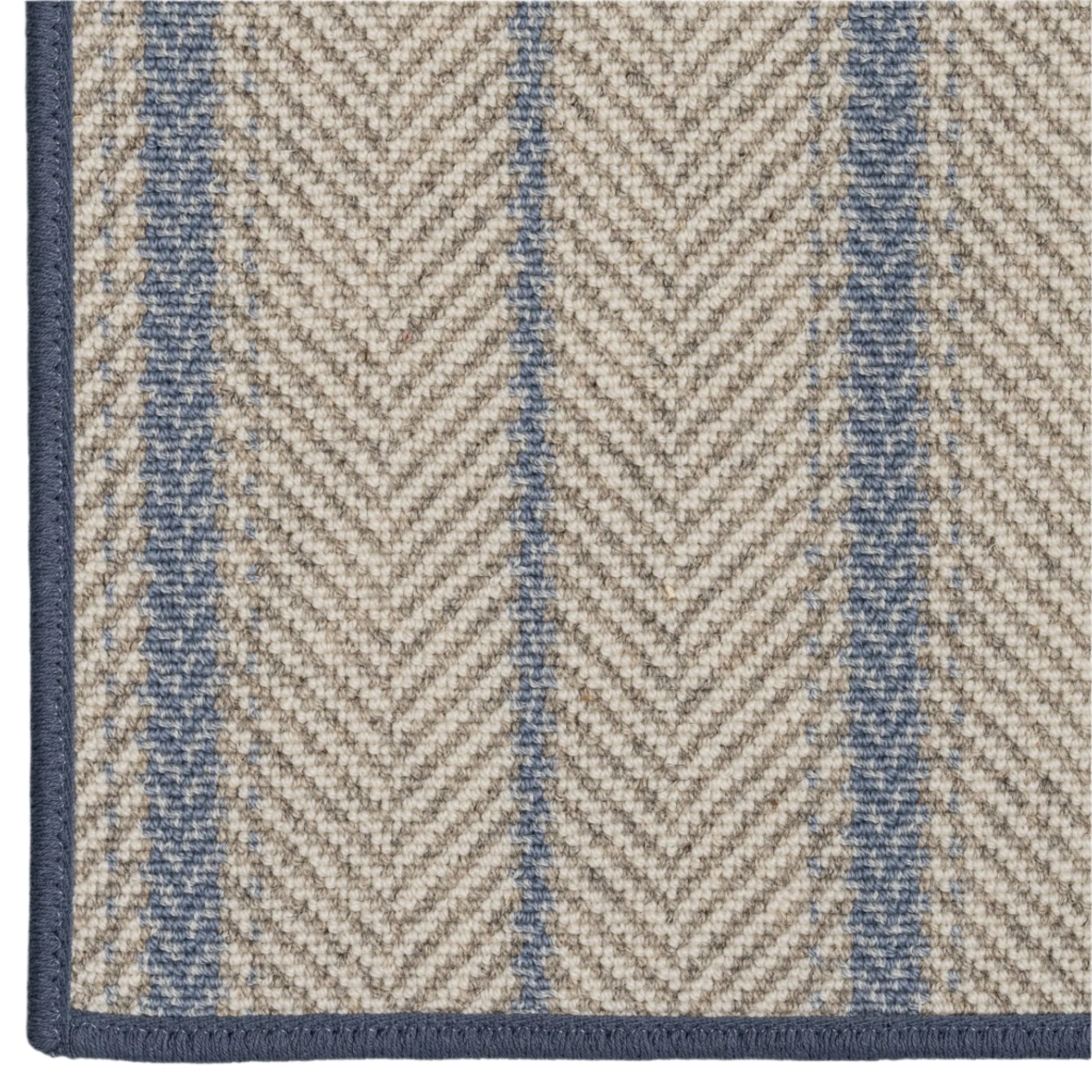 Close-up of a rug with a herringbone pattern in beige and blue.
