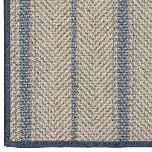 Close-up of a rug with a herringbone pattern in beige and blue.