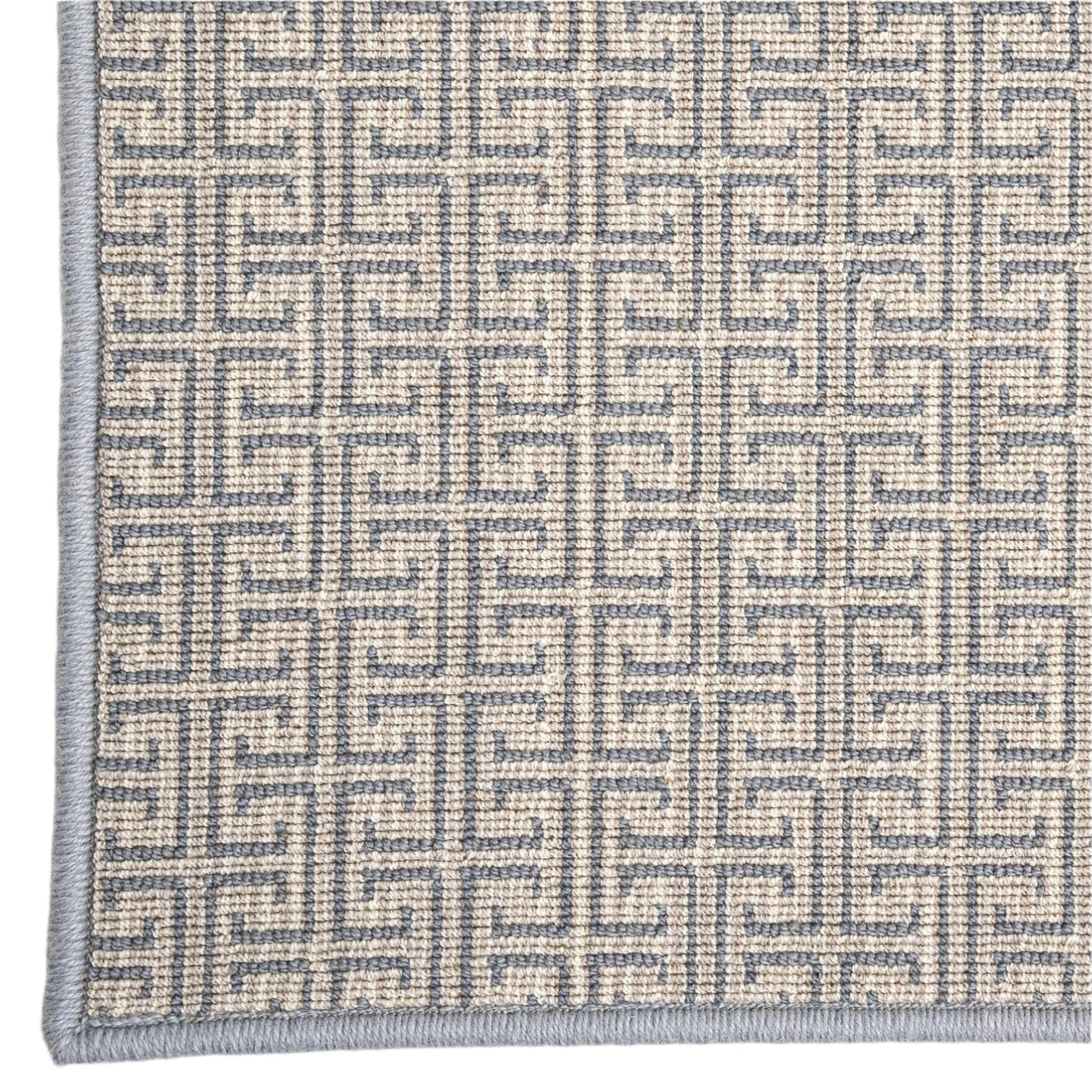 Close-up of a textured rug with a geometric pattern on a plain background